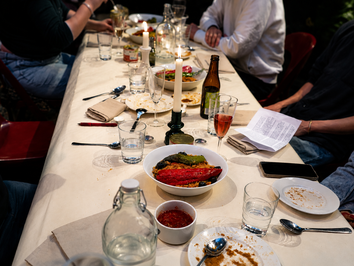 photo d'une table de diner. La nappe est blanche. nous voyons seulement les bras des convives. Le repas a commencé.